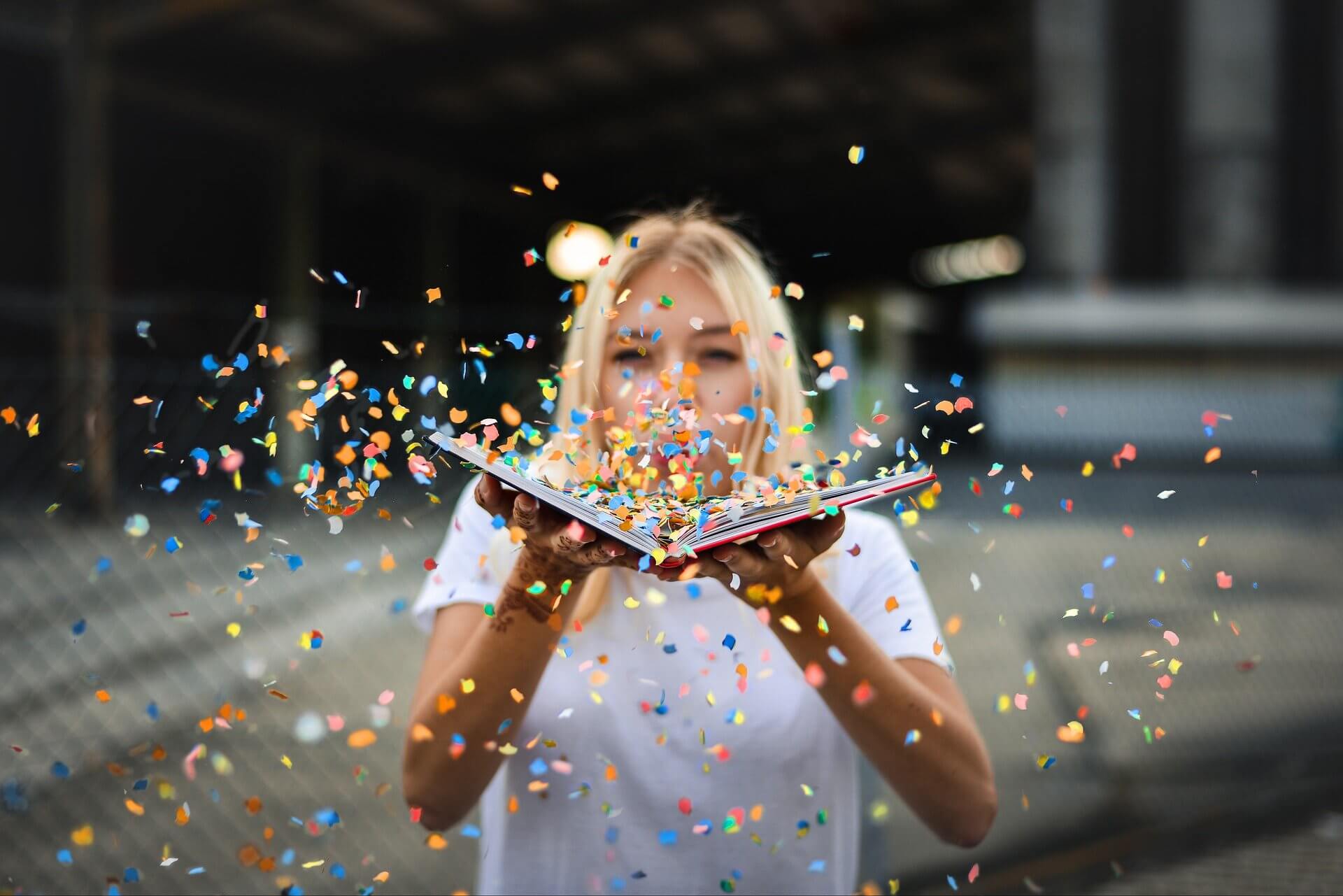 A woman blowing confetti out of a book