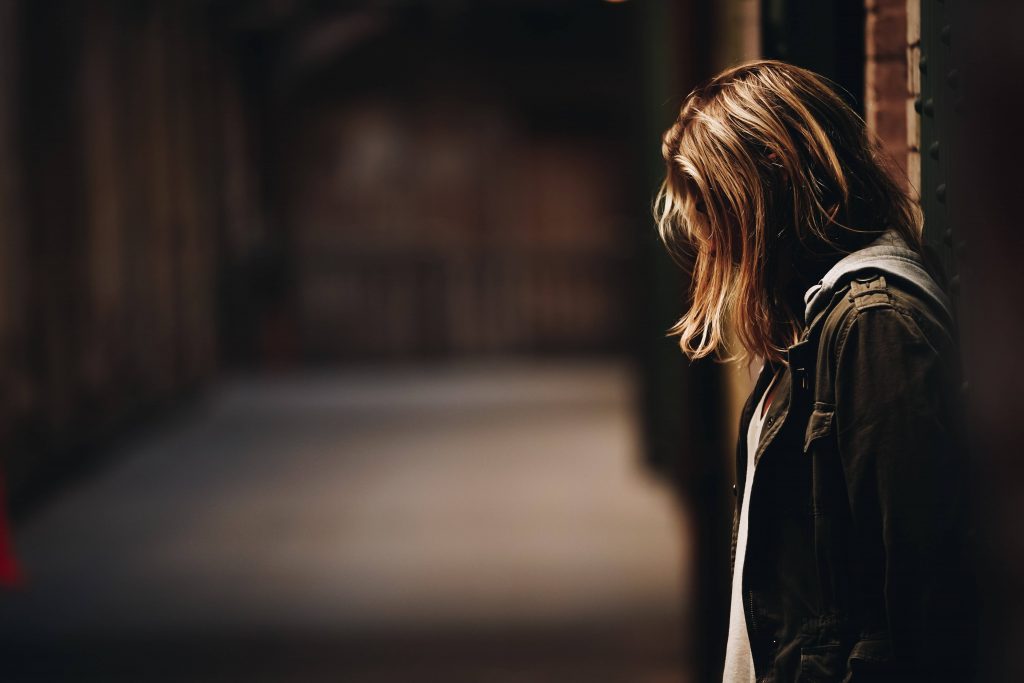 A woman leaning against a wall in a dark alley